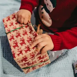 A wrapped Christmas gift being opened by a small child